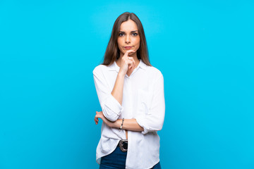 Young woman over isolated blue background thinking