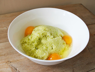 Dough for zucchini fritters pancakes preparation. Eggs and grated vegetables. Cooking concept