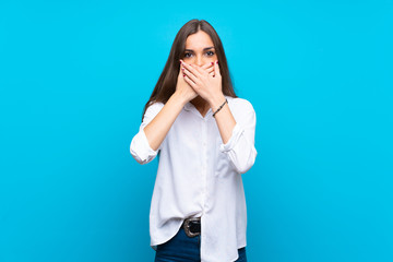 Young woman over isolated blue background covering mouth with hands