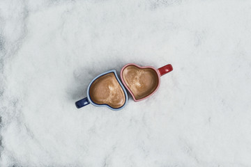 two cup of coffee in the heart form in the snow. New Year Christmas and winter concept