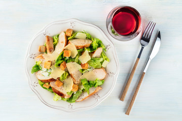 Chicken Caesar salad, overhead shot with a glass of wine