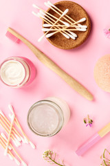 Plastic-free, zero waste cosmetics, flat lay pattern on a pink background. Bamboo toothbrushes and cotton swabs, homemade creams etc, shot from above