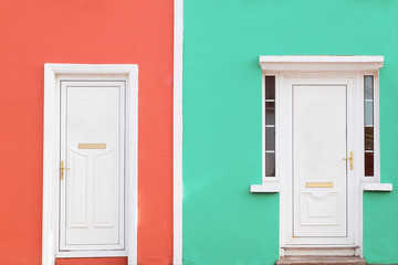 Facade colored in coral and mint colors with two white doors.