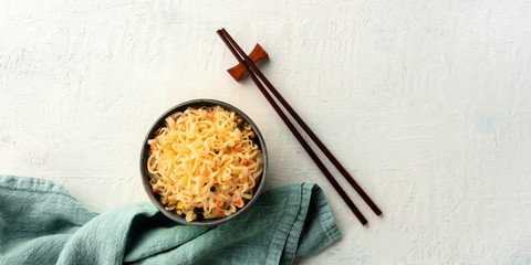 A panorama of instant soba noodles with carrot, shot from the top with chopsticks and copy space. A metaphor for a dinner for one