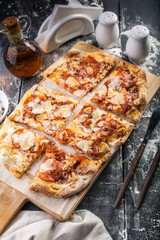 Peperroni pizza on a cutting board on a dark wooden table. Close-up. Vertical shot
