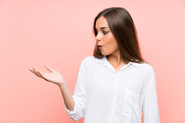Young woman over isolated pink background holding copyspace imaginary on the palm