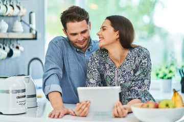 Couple in home kitchen using electronic tablet