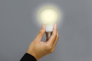 Hand holding a glowing light bulb