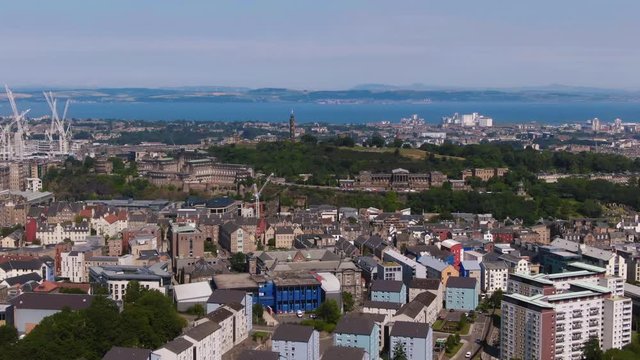 Aerial pull back view of Calton hill in Edinburgh and the firth of forth