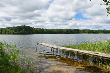 Fototapeta na wymiar Wooden bridge by the lake, boat mooring