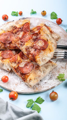 Vertical shot peperroni pizza on a cutting board on a blue background. Close-up
