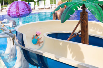 Fototapeta na wymiar Little girl at the water slide on sun holidays