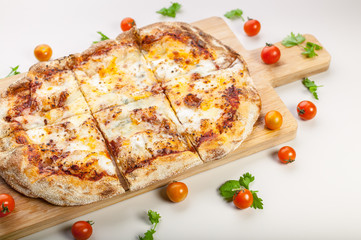 Pizza Quattro formaggi on a cutting board with cherry tomatoes and herbs