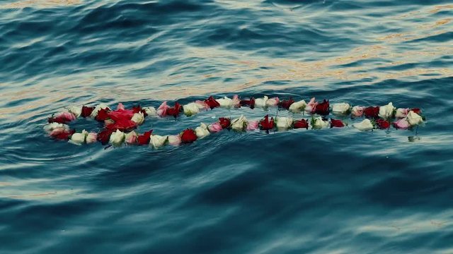 Memory concept. A wreath of flowers floating in the water.