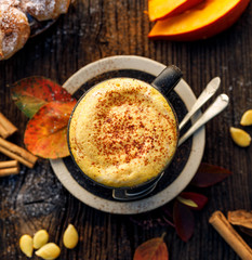 Pumpkin spice latte, coffee with the addition of pumpkin puree, aromatic spices,  sprinkled with cinnamon  in a cup on a wooden table, top view. Delicious and healthy hot drink