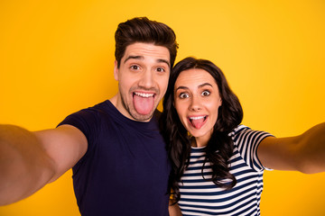 Fototapeta premium Self portrait of nice lovely charming couple of two people showing tongue while isolated with yellow background