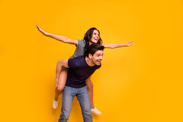 Fototapeta na wymiar Photo of style stylish trendy cheerful nice cute couple of two people wearing t-shirt dress pretending to fly while isolated with background yellow