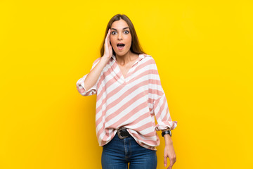 Young woman over isolated yellow background with surprise and shocked facial expression