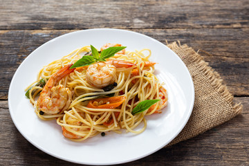 Spaghetti with spicy fried shrimp on a wooden table