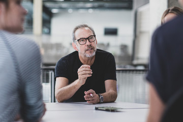 Mature adult male leading a meeting at a tech company