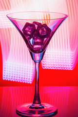 Martini glass with ice on red abstract background. Close up.