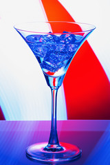 Martini glass with ice on red and blue abstract background. Close up. Selective focus.