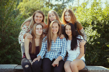 Different and happy in their bodies. Young women smiling, talking, walking and having fun together outdoors on sunny summer's day at park. Girl power, feminism, women's rights, friendship concept.
