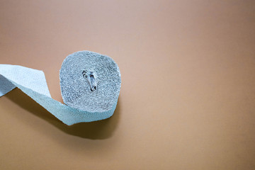 Rough toilet paper role fabricated from recycled paper on brown surface .