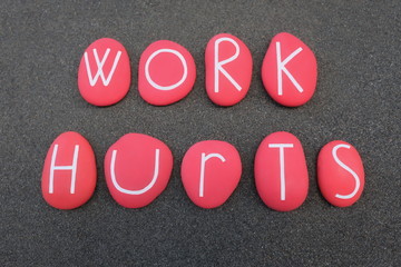 Work Hurts phrase composed with red colored stones over black volcanic sand