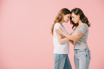 side view of attractive women in t-shirts hugging isolated on pink