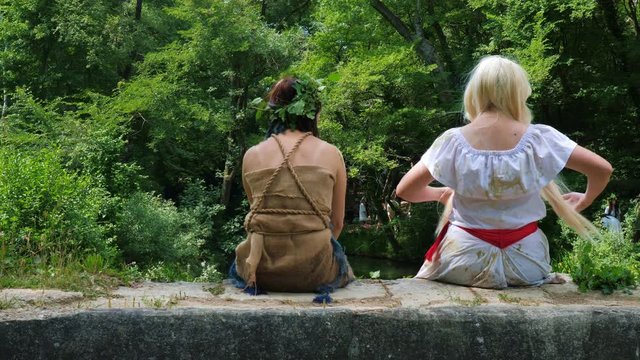 Two girls in cosplay images in nature. Close view from the back.