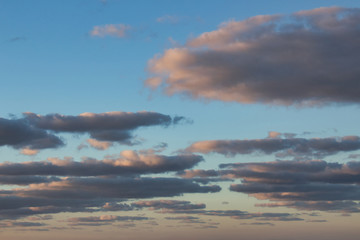 Obraz na płótnie Canvas Fluffy flat clouds against a blue sky during golden hour