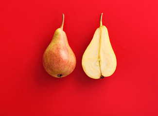 Couple of fresh pears, whole and sliced on a red background. Top view