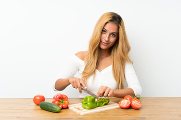 Young blonde woman with vegetables in a table