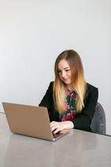 Pretty young girl working at computer in office, white background, copy space