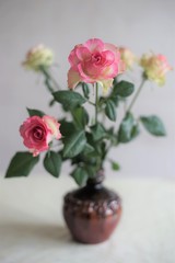Bouquet of pale pink yellow roses in a ceramic vase on a table, side view