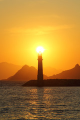 Seascape at sunset. Lighthouse on the coast. Seaside town of Turgutreis and spectacular sunsets