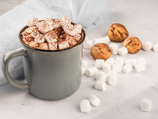 Hot chocolate in a gray mug with cookies on a concrete surface.