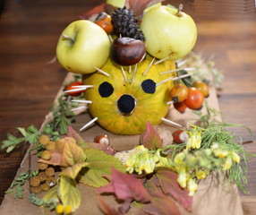Naklejka na ściany i meble Gifts of Autumn. Craft pumpkin hedgehog, decorated with apples, nuts, chestnuts, cones, rose hips.