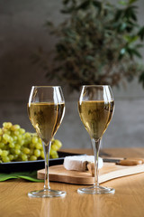 Pouring white wine into the glass against wooden background