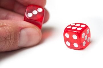 Closeup of red dice in hand on white background