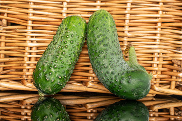 Group of two whole siamese fresh pickling cucumber with braided rattan behind