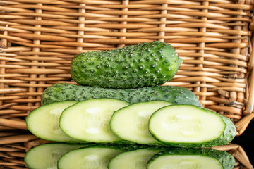 Group of two whole four slices of meaty fresh pickling cucumber with braided rattan behind