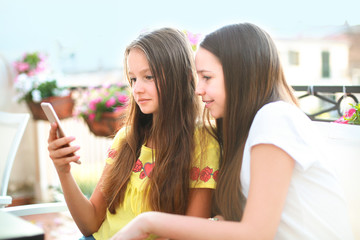Outdoor funny portrait of two teen girls making grimaces flirting and showing tongue, posing on camera. Concept of stylish outfits friendship, joy, sisters, positive.