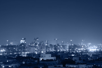 Fototapeta na wymiar Night view of the city life. Light of the buildings shining with cool blue tones. View of night scene of Tel Aviv, Israel. Blue tone city scape.
