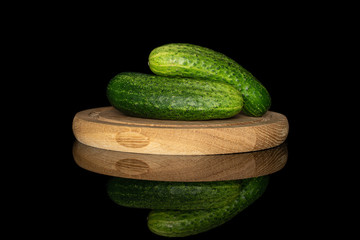 Group of two whole fresh green pickling cucumber on bamboo plate isolated on black glass