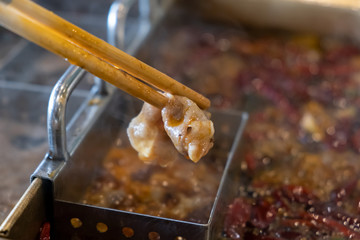 Beef sliced in chopsticks boiling in hot and spicy red chili soup called 