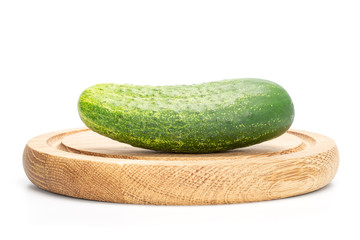 One whole fresh green pickling cucumber on bamboo plate isolated on white background