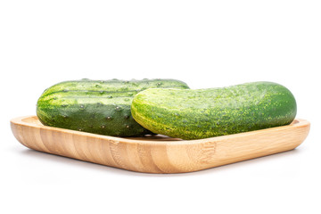 Group of two whole fresh green pickling cucumber on wooden square plate isolated on white background