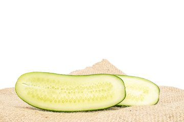 Group of two halves of fresh green pickling cucumber on jute cloth isolated on white background